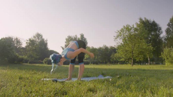 一个夏天的早晨，一位迷人的瑜伽老师正在公园的瑜伽垫上练习