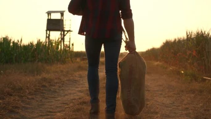 日落时分，SLO MO Farmer在一条土路上背着一袋玉米