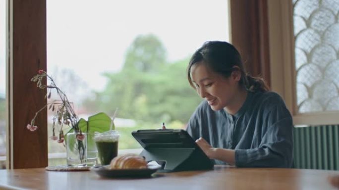 亚洲妇女在咖啡店使用数字平板电脑