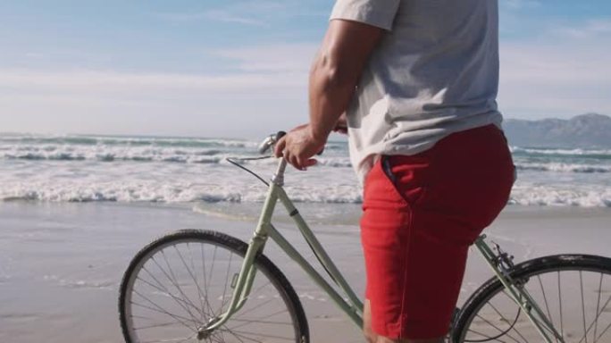 资深非裔男子骑自行车在海滩散步