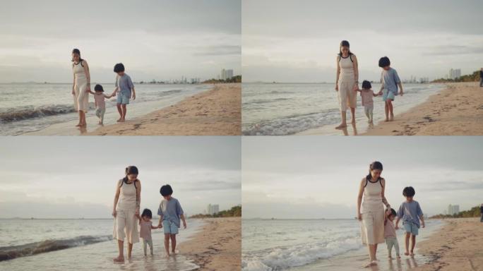 在阳光明媚的日子里，年轻的亚洲妇女和两个可爱的孩子在海边散步。