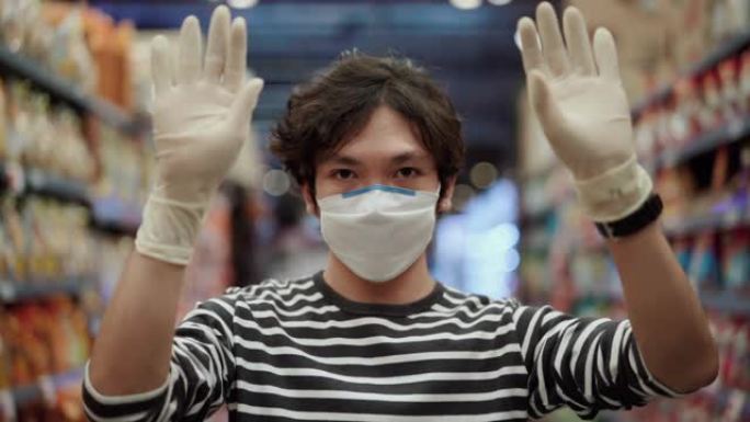 年轻男子戴防护口罩使用防护手套在超市购物