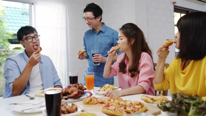 年轻的朋友聚会，一起坐在家里的餐桌旁，吃披萨食物，笑着吃饭。