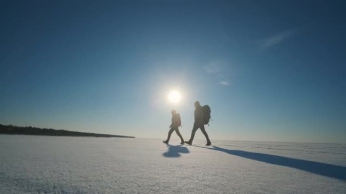 两个旅行者穿过雪原。慢动作