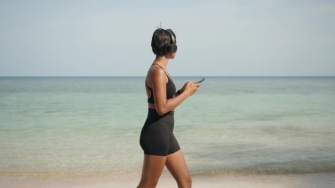 穿着运动服的女人在海滩上使用电话