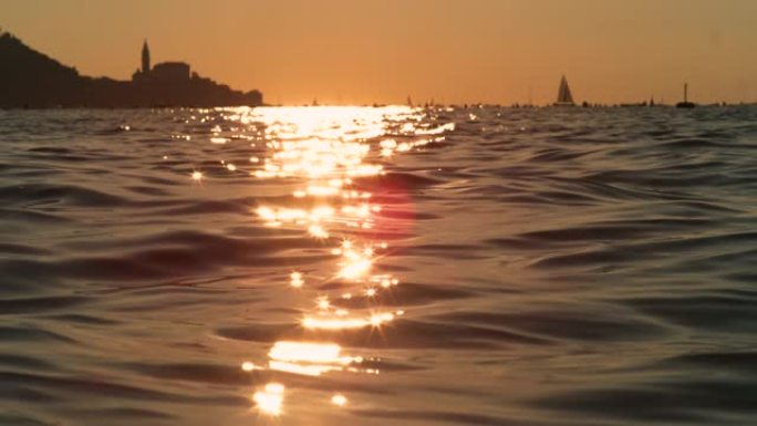 镜头耀斑: 皮兰附近的亚得里亚海在金色的夏日傍晚阳光下闪闪发光