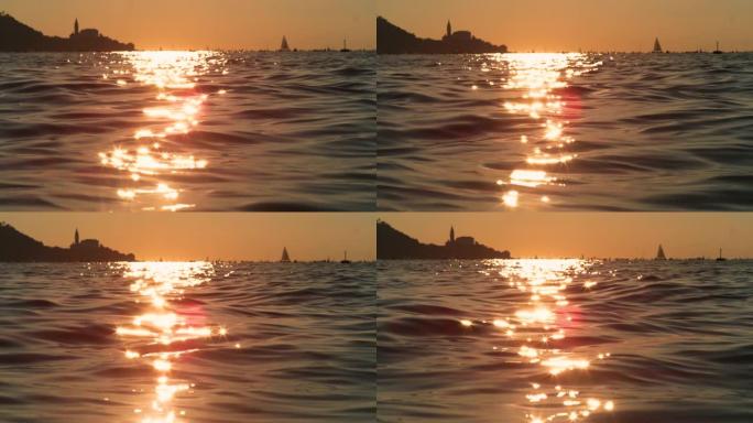 镜头耀斑: 皮兰附近的亚得里亚海在金色的夏日傍晚阳光下闪闪发光