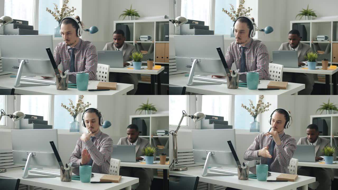 快乐的员工使用电脑打字，然后在办公室通过耳机跳舞欣赏音乐