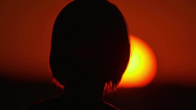 女人 (剪影) 站在明亮的太阳和天空背景下。特写