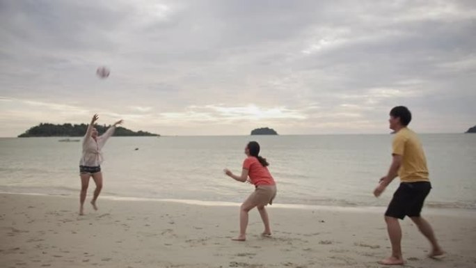 一群亚洲年轻男女一起在沙滩上踢足球