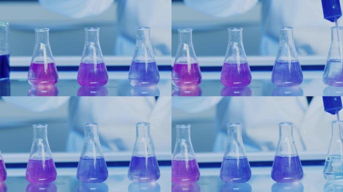 变色液体化学实验室的医学研究实验。注射器的特写镜头将蓝色碱性或酸性化学物质倒入erlenmeyer烧