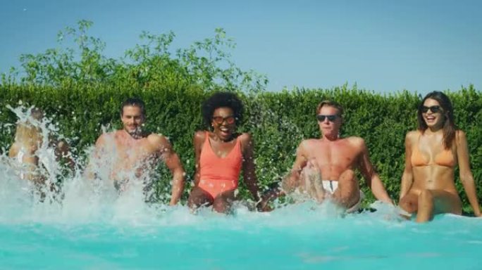 穿着泳装的多民族年轻朋友的慢动作很有趣，可以在游泳池里一起享受暑假，并在阳光明媚的日子里跳舞。