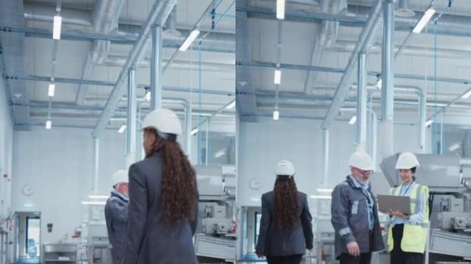 垂直屏幕: 两名专业的重工业员工在工厂戴着安全帽。讨论工业生产，使用笔记本电脑。亚洲工程师和中年技术