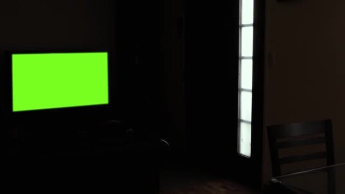 在黑暗的客厅中，黑色墙壁上的绿色屏幕LED电视。放大。