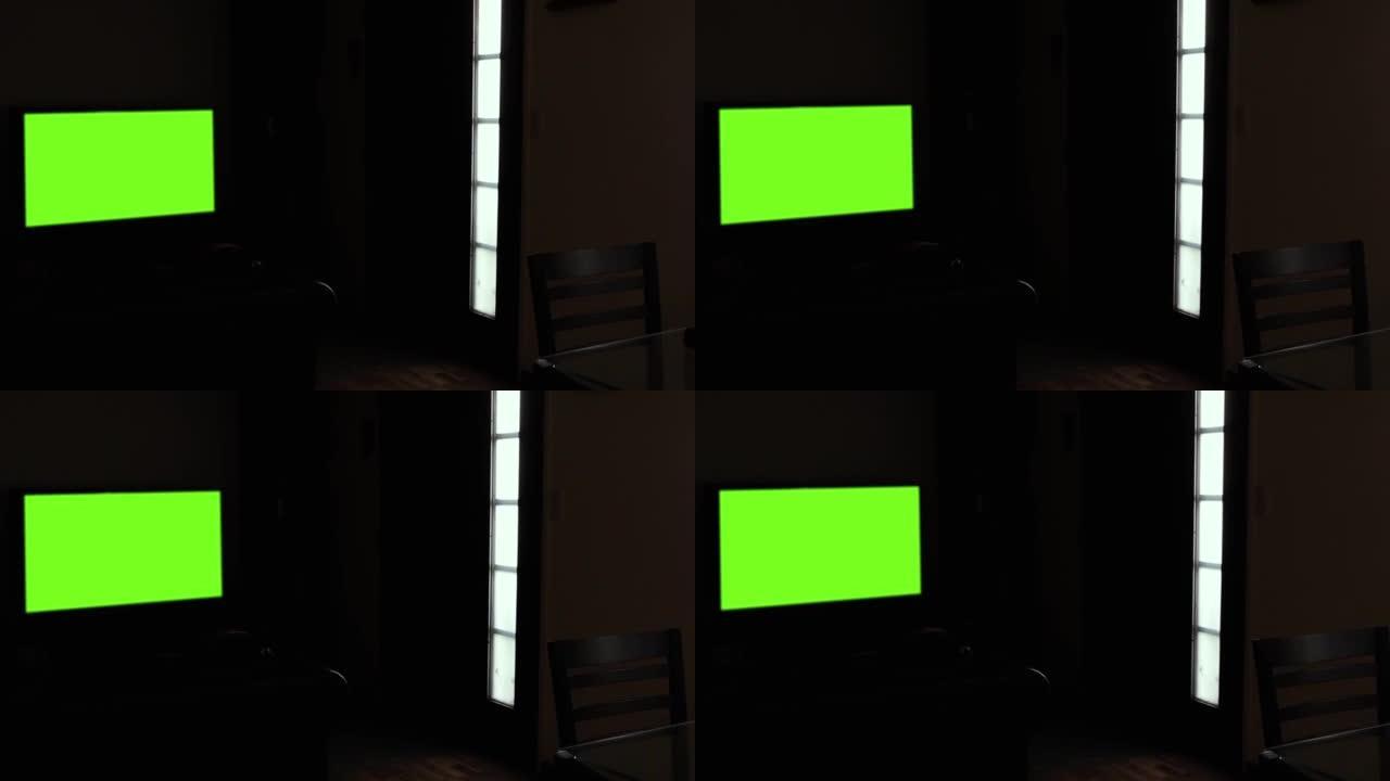 在黑暗的客厅中，黑色墙壁上的绿色屏幕LED电视。放大。