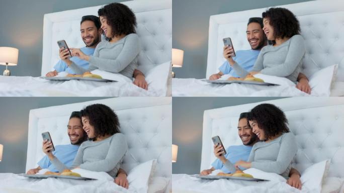 智能手机，大笑和情侣躺在床上放松，并在社交媒体或互联网上观看视频。快乐，技术和年轻的男人和女人在卧室