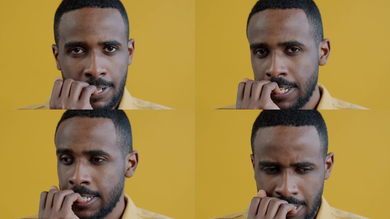 紧张的非洲裔美国男子咬指甲看着相机的特写肖像