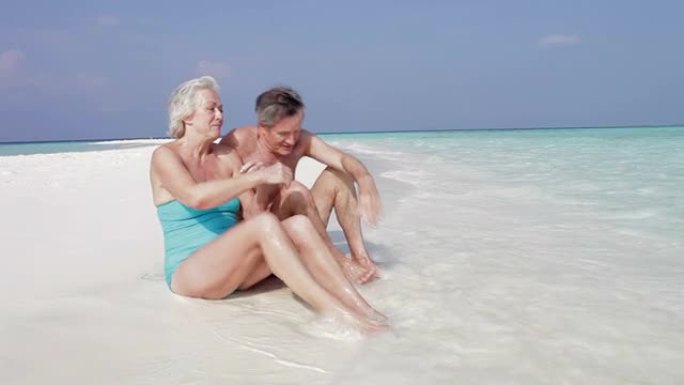 坐在美丽海滩上的高级夫妇
