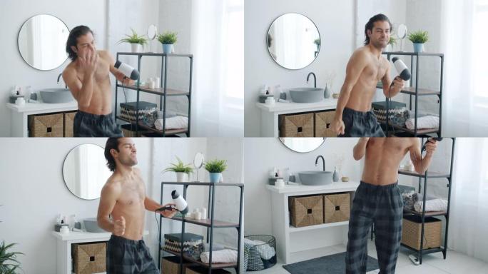 快乐的家伙在家里的浴室里用吹风机跳舞和唱歌吹干头发的慢动作