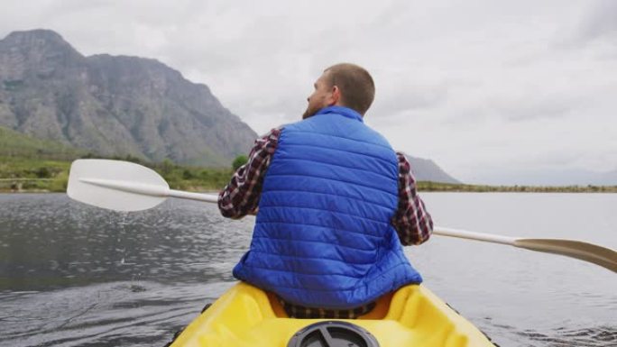 高加索人在山上旅行时玩得很开心，在湖上划皮艇，拿着桨
