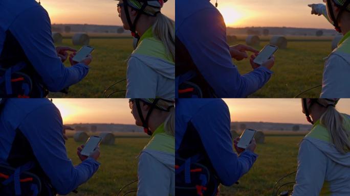 SLO MO几个骑自行车的人在用手指指向远处某个地方时使用智能手机