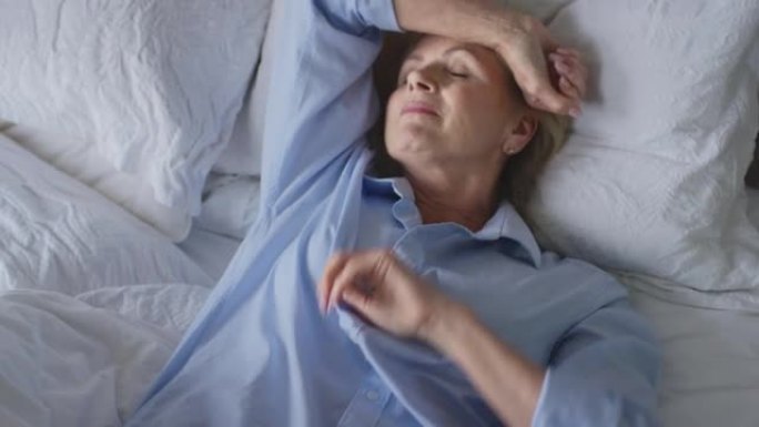 患有失眠的更年期成熟妇女在家中躺在床上醒来-慢动作射击