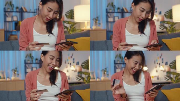 夜晚美丽微笑的亚洲女士在客厅沙发上使用手机订购带信用卡的网上购物产品。