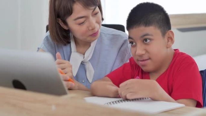 亚洲残疾男孩与亚洲年轻女性交谈照顾者在家通过电脑帮助家庭教育。残疾收集2019