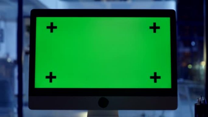 晚上在公司办公室中带有绿屏复印空间和标记的计算机屏幕。具有在线资源和研究材料的色度键台式机，可用于公