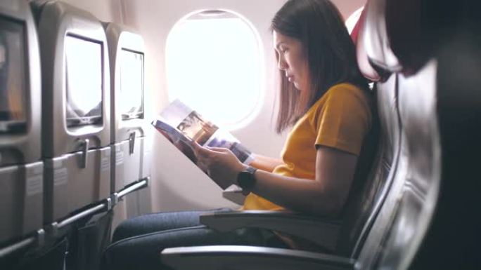 女乘客阅读杂志，在飞机上放松，慢动作
