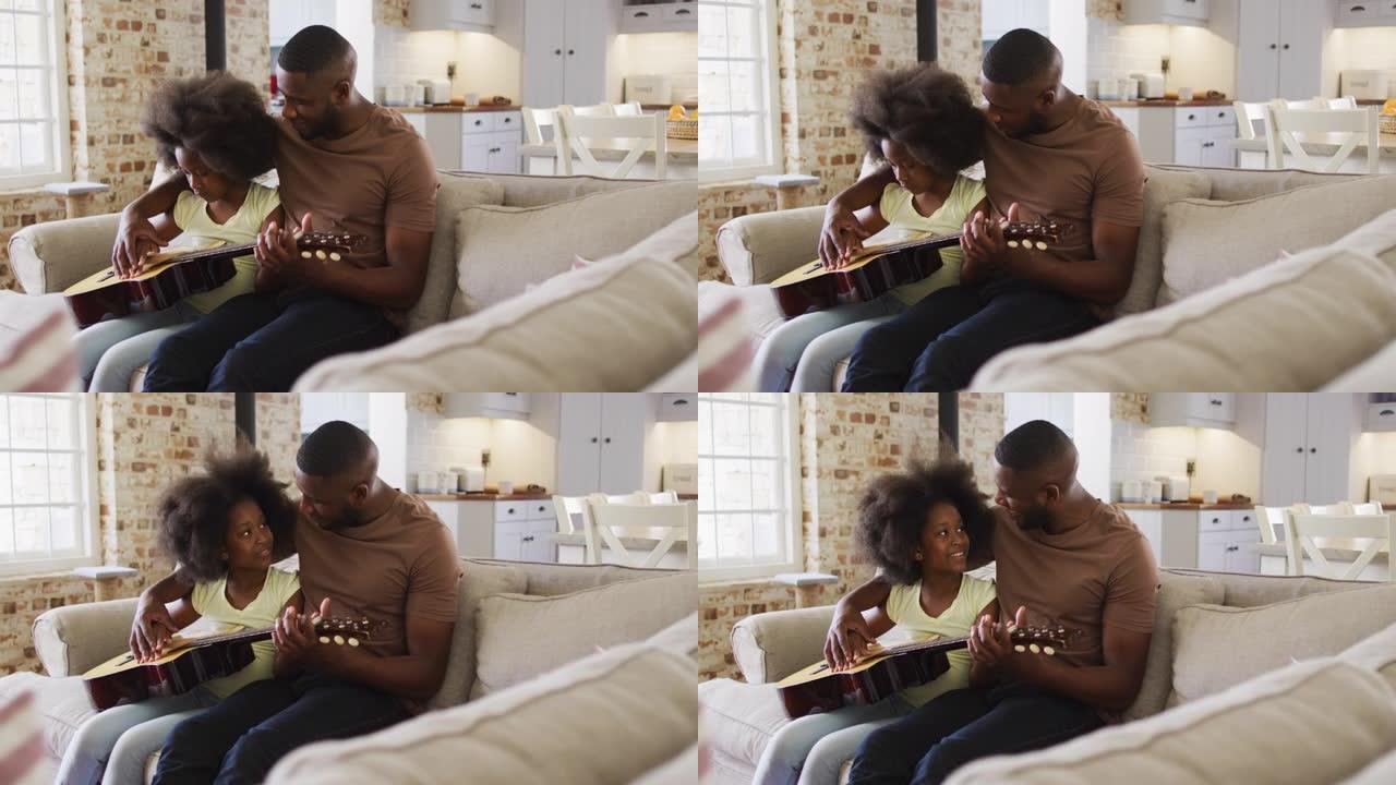 非裔美国父亲和他的女儿坐在沙发上一起弹吉他