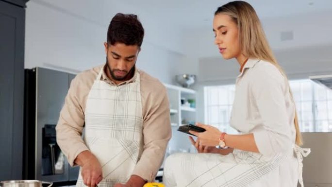 夫妻，烹饪和阅读平板电脑的在线食谱，教程或视频，同时帮助在厨房切蔬菜烹饪健康的食物。男人和女人在欧洲