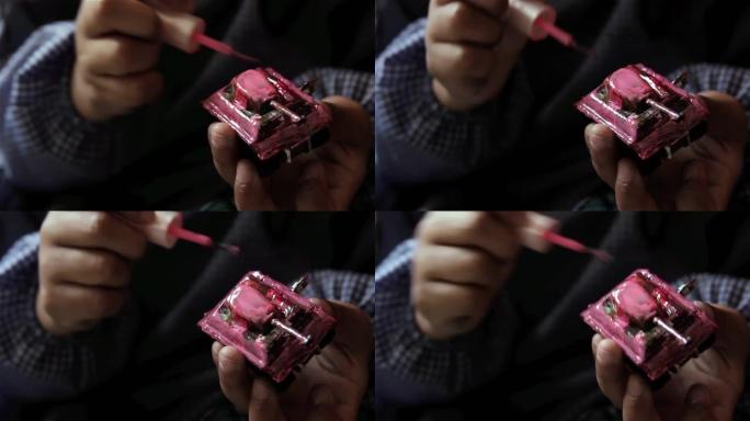一个年轻女孩的手用指甲油画一个玩具坦克，女孩在模型坦克上涂上油漆。特写。4k分辨率。
