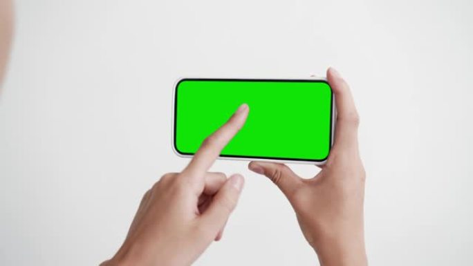 年轻人看屏幕智能手机与绿色色度键特写。女孩手里拿着点击手机模型POV。概念观看节目电影，互联网社交媒