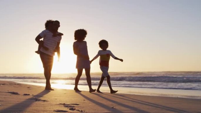 日落时分在海滩上一起散步的非裔美国人家庭
