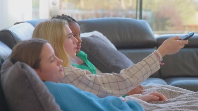 一群无聊的十几岁的女孩朋友在家看电视，并在频道中轻弹，试图找到可以观看的东西-慢动作拍摄