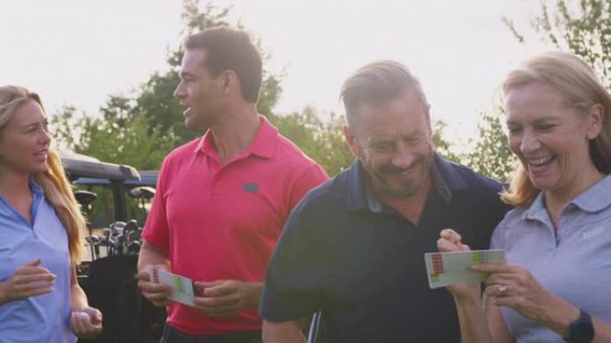 成熟和中年夫妇站在高尔夫球车旁边一起检查记分卡