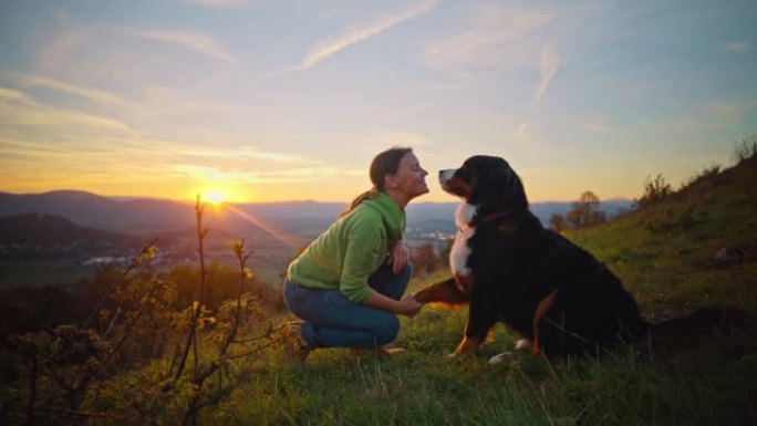 日落时分，SLO MO女人与她的狗在山顶上结为纽带