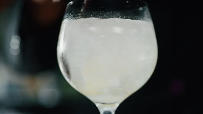 专业调酒师的特写镜头是在酒吧或迪斯科俱乐部向顾客混合杜松子酒补品和专业水晶冰块。