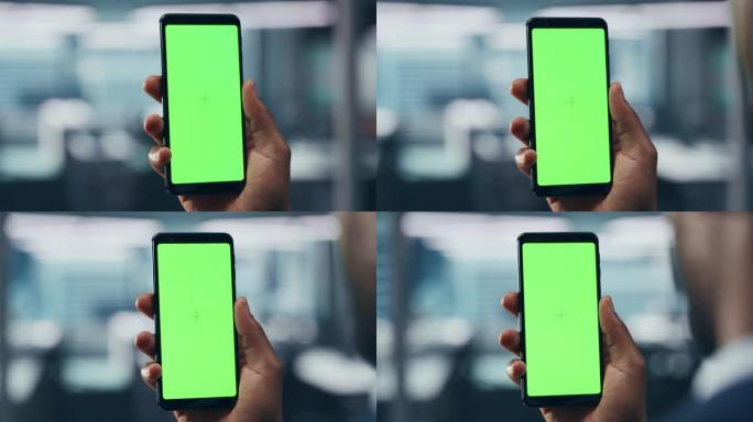 办公室里有绿屏色度键智能手机的黑人。非裔美国人使用互联网、社交媒体、手机设备在线购物。专注于展示，手