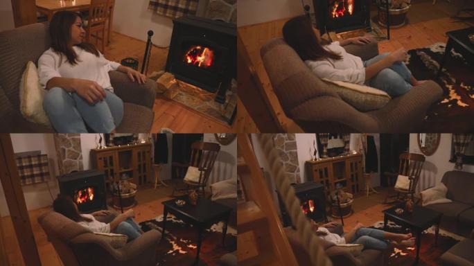 女人在家里壁炉旁舒适的扶手椅上放松