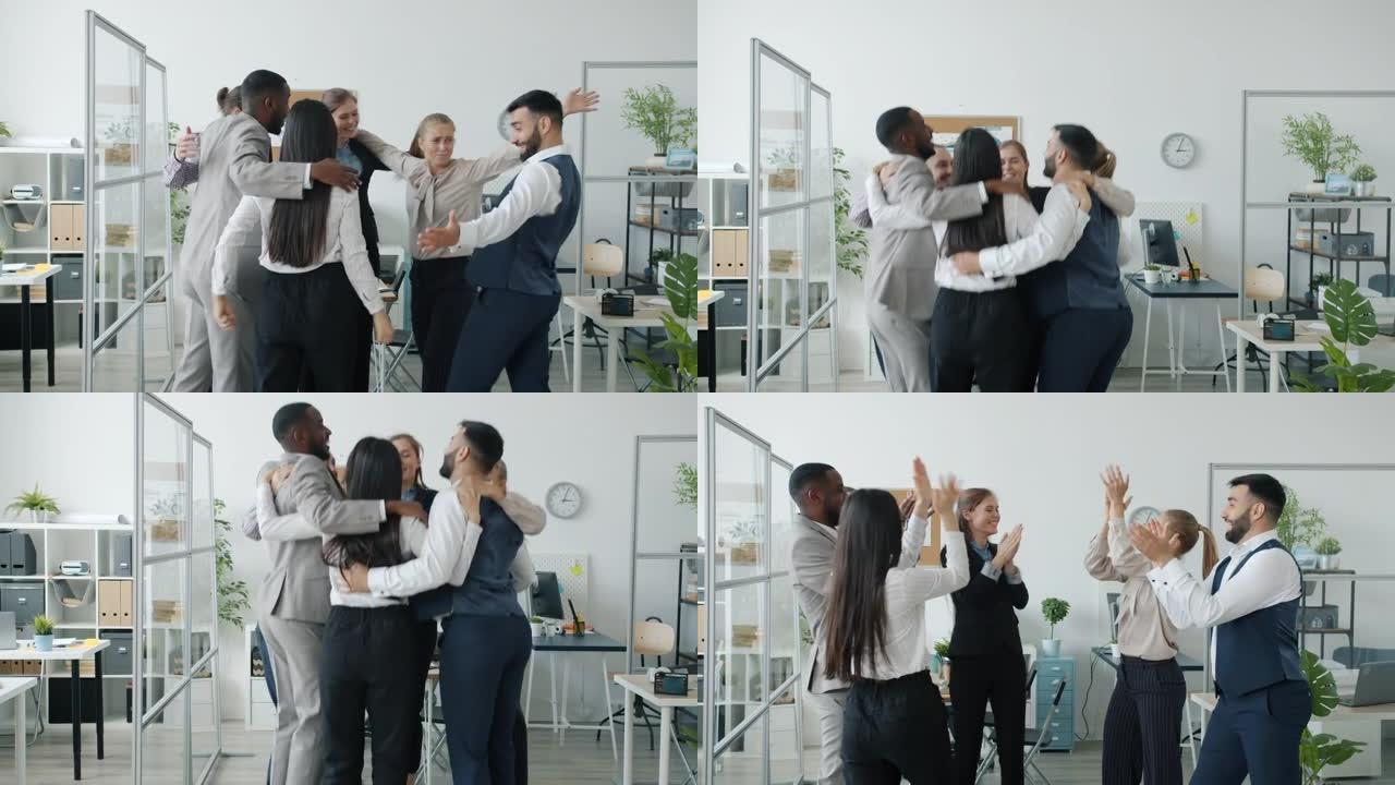 多种族的人们跳着拥抱，然后在办公室拍手