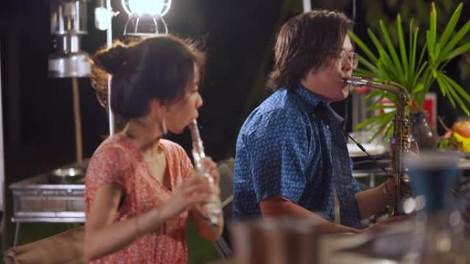 亚洲华裔情侣音乐家晚上喜欢演奏乐器花园派对聚会露营帐篷