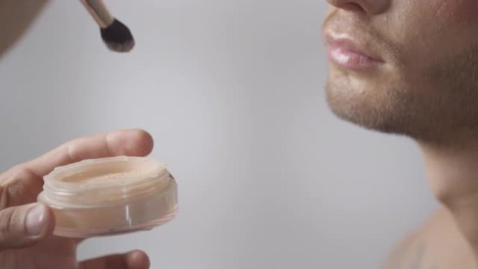 MUA在男性客户脸上涂抹定型粉