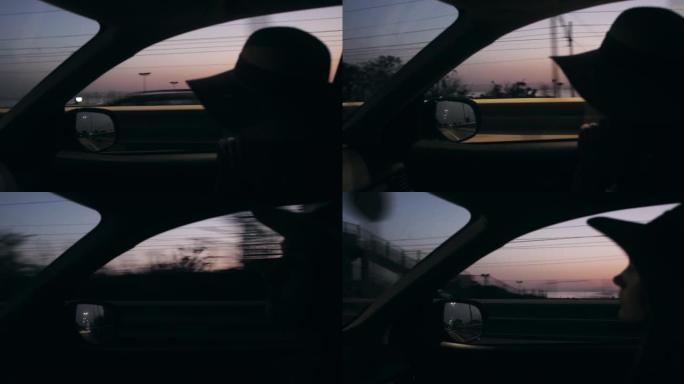 在日出海路慢动作驾驶的汽车乘客座位上戴着夏日帽子的美女特写剪影拍摄。
