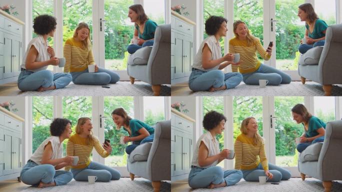 三个女人在家里的休息室里放松，喝咖啡，看手机上的照片或视频-慢动作拍摄