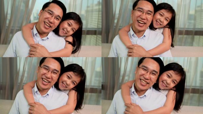 女儿抱着父亲，看着镜头，然后带着开朗的心情对着镜头微笑
