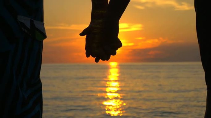 恋爱中的情侣在海边日落时牵手
