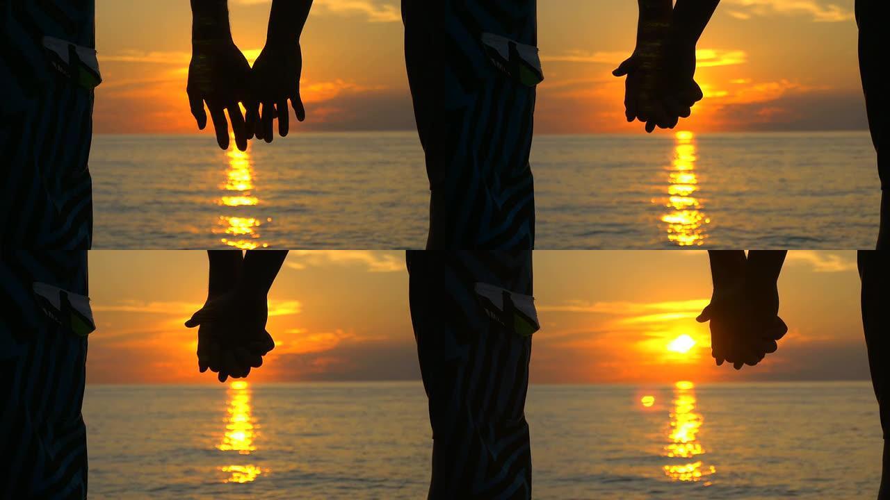 恋爱中的情侣在海边日落时牵手