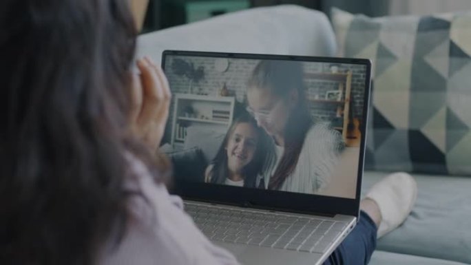 年轻妇女和儿童在家里使用笔记本电脑进行在线视频通话聊天和大笑